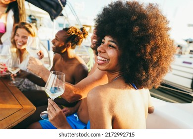 Felices amigos multirraciales divirtiéndose bebiendo vino en una fiesta en barco al aire libre - Enfoque suave en la cara de una niña africana