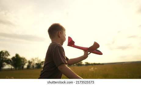 boy kid run in the park across the field play with an toy airplane in his hand a silhouette at sunset wants to astronaut pilot. fun fantasy dream kid concept. child run wheat play fun with toy