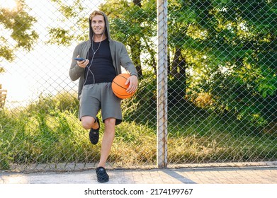 Esportivo com bola para jogar basquete, ouvindo música em fones