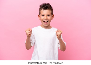 Little caucasian boy isolated on pink background celebrating a victory in winner position