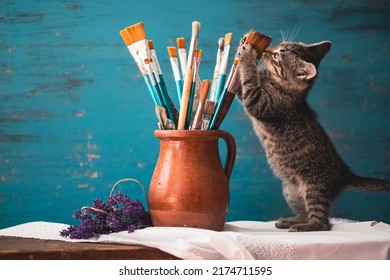 Stilleven van verfborstels in kleikruik, lavendelbloemen en een leuk katje op vintage turkooizen achtergrond