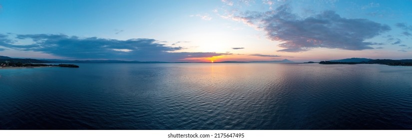 Nascer do sol sobre vista panorâmica aérea do oceano calmo. Paisagem marítima dramática do pôr do sol no Mar Egeu. Tons de laranja e azul céu nublado. Chalkidiki, Grécia