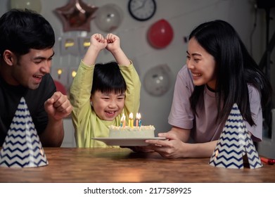 Une famille asiatique heureuse fête un anniversaire à la maison. Un petit garçon souffle les bougies de son gâteau d'anniversaire avec ses parents. Concept de vie urbaine pour une petite famille asiatique heureuse.