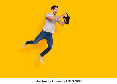 Full body foto van onder de indruk brunet jonge kerel jump drive dragen t-shirt jeans schoenen geïsoleerd op gele achtergrond