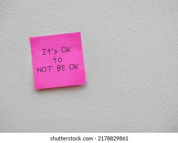 Torn note paper stick on red copy space background with text written IT'S OK TO NOT BE OK, means feelings and emotions expressing are valid no matter what they are, its normal to say you are not okay