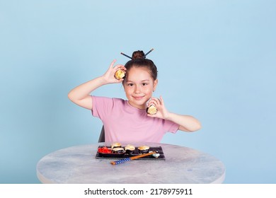 Cute smiling little girl with with sushi on red background. Student child girl eating sushi and rolls - commercial concept.