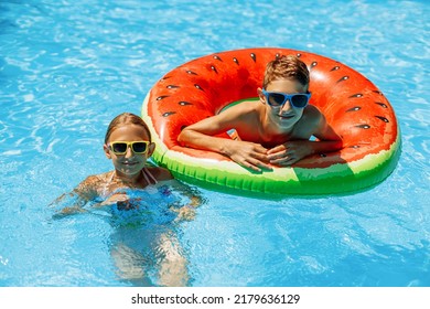 jongen en een meisje in zonnebril zwemmen in het buitenzwembad. Zomervakantie met kinderen. Zwemhulpmiddelen en kinderkleding. water speelgoed. Een klein kind drijft op een kleurrijk vlot.