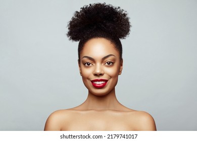 Encantado Joven hermosa modelo afroamericana con moño contra el fondo gris. Sonrisa perfecta.