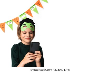Un niño con una máscara de Hulk sostiene un teléfono en sus manos y sonríe con un fondo blanco. fiesta de Halloween