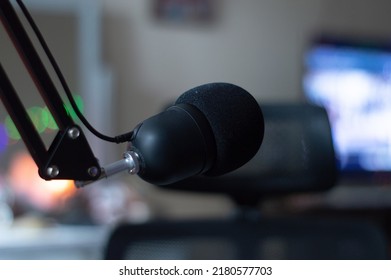 Merekam mikrofon dengan studio menyala dan monitor di latar belakang