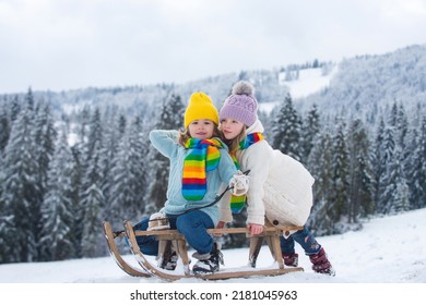 Anak laki-laki dan perempuan naik eretan di hutan bersalju. Anak-anak musim dingin di luar ruangan bersenang-senang untuk Natal dan Tahun Baru. Anak-anak menikmati naik kereta luncur. Pemandangan Natal.