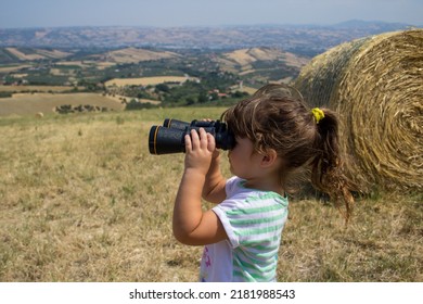 双眼鏡で地平線を見ているオープン フィールドの愛らしい少女のイメージ。