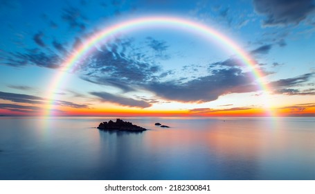 Long exposure image of dramatic sky and seascape with rock at sunset, Amazing rainbow in the background 