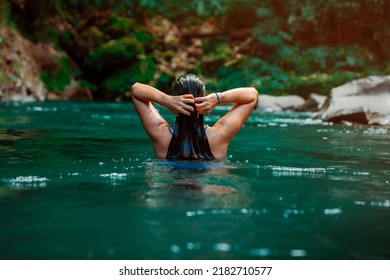 young Latina woman swimming in Rio Fortuna in Costa Rica with totally wet long hair. High quality photo
