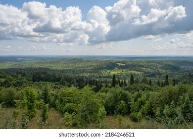 夏のホワイト マウンテン (ロシアのペルミ地方) の頂上からのウラルの果てしない森の眺め。自然の美しさは、水平線の靄と、エンボス加工された雲のある青い空によって引き立てられます