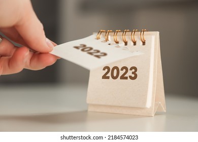 a woman's hand turns over a calendar sheet. year change from 2022 to 2023.