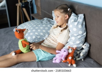 a girl of eight years old plays with knitted toys in the room
