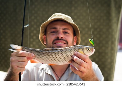 あごひげを生やした男は獲れたチャブ魚を餌につかむ