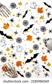 Happy Halloween holiday concept. Pattern made of Halloween decorations, bats, skeleton hands, ghosts, spiders, webs on white background. Flat lay, top view.