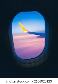 De vleugel van het vliegtuig en de lucht, paarse wolken, het uitzicht vanuit het raam van het vliegtuig tijdens de vlucht