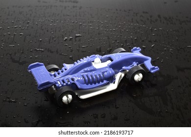 Detská hračka, pretekárske auto v modrej farbe na tmavej ceste.