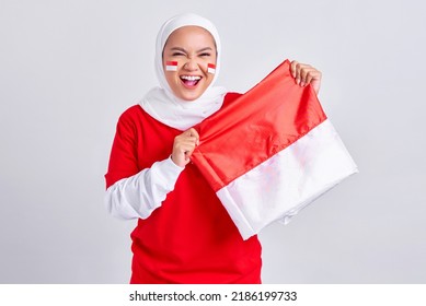 Wanita muda muslim Asia yang tersenyum dengan kaos merah putih merayakan hari kemerdekaan indonesia pada 17 Agustus dengan bangga menunjukkan bendera indonesia yang terisolasi dengan latar belakang putih