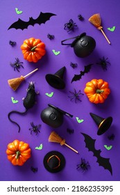 Happy Halloween holiday concept. Pattern made of Halloween decorations, pumpkins, bats, spiders, witch hats and brooms on purple background. Flat lay, top view.