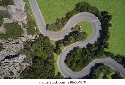Vista aérea de un camino sinuoso rodeado de árboles y prados verdes. Vista aérea de un camino sinuoso en las montañas.