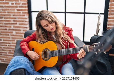 Jonge vrouwenmusicus die klassieke gitaar speelt bij muziekstudio