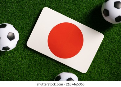 Flag of Japan. Football balls on a green lawn. World Cup 2022. Top view.