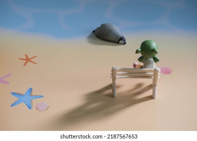 Nhân vật hoạt hình cô gái ngồi trên ghế trắng và chim cánh cụt ngủ phía trước trên bờ biển.