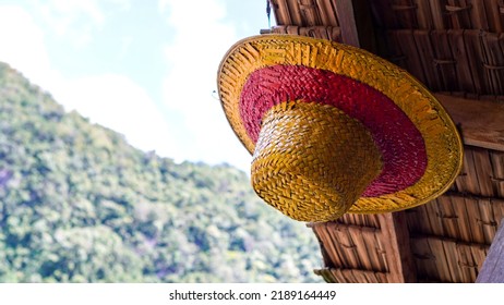 Strohhut mit roten Streifen, der an einer Holzstange hängt. Strohhut mit Hügeln im Hintergrund. Luffy Mugiwaras Strohhut