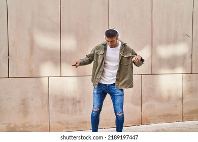 Young hispanic man smiling confident listening to music and dancing at street