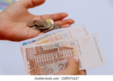 Kroatische kuna en munten lipa in de handen van een vrouw op een witte achtergrond.