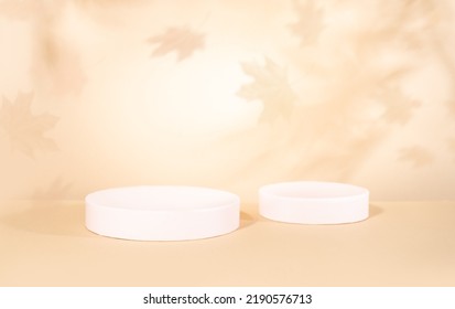 Concepto de otoño con podios cilíndricos para la presentación de productos promocionales. Formas geométricas y sombras de las hojas del arce en una pared. Escena otoñal abstracta con espacio para copiar.