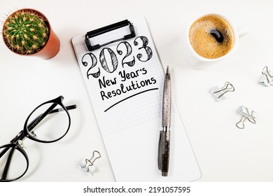 Nieuwe jaarresoluties 2023 op bureau. Lijst met resoluties voor 2023 met notitieboekje, koffiekopje op witte tafel. Doelen, resoluties, plan, actie, checklist concept. Nieuwjaar 2023 kaart bovenaanzicht