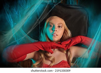 ハロウィンの話。魔女の衣装を着たかなり金髪の女の子が、恐ろしいクモの巣に囲まれた古い家に立っています。ハロウィンの飾り付け。