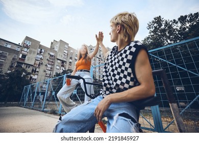 Amigos adolescentes estão sentados na área externa da cidade e dão "toca aqui" um ao outro.