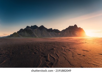 Goldener Sonnenaufgang am Berg Vestrahorn am Atlantik und am schwarzen Sandstrand am Morgen auf der Halbinsel Stokksnes, Island