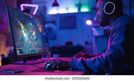 Jucător entuziasmat care joacă un joc video de strategie PRG în care jucătorii luptă într-un turneu Battle Royale pe computerul său personal. Cameră și PC cu lumini neon. Negru elegant într-o cameră confortabilă acasă.