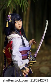 Retrato de una hermosa joven cosplay con traje samurai en el jardín japonés