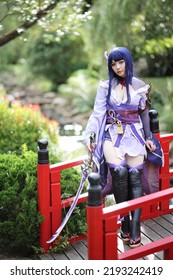 Retrato de una hermosa joven cosplay con traje samurai en el jardín japonés