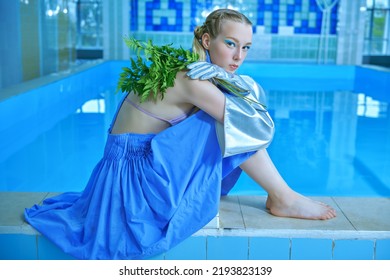 Retrato de moda de una hermosa modelo de moda con maquillaje de ojos turquesa posando con un vestido de diseñador azul y guantes en la piscina. Estilo y belleza de verano.
