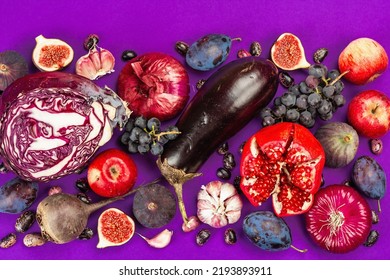 青、赤、紫の食べ物。果物と野菜の料理の背景。新鮮なイチジク、プラム、タマネギ、ナス、ブドウ、キャベツ、リンゴ、ニンニク、ハナミズキ、ザクロ、ビーツ。紫色の背景、フラット レイアウト