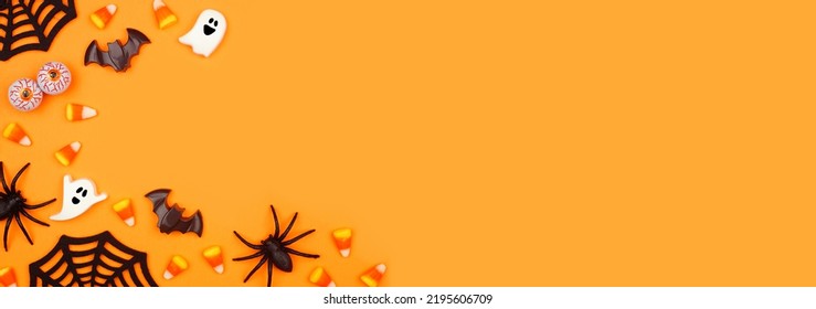 Halloween corner border of scattered candy and decor. Above view over an orange banner background with copy space.