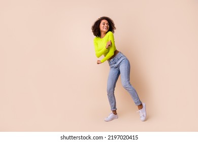 Full size photo of young smiling joy lady wear yellow top jeans dancing new open party show isolated on beige color background