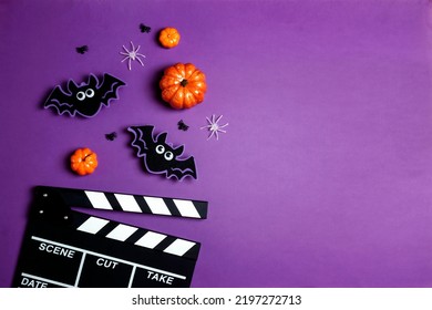 コピー スペースと紫色の背景にハロウィーンの装飾が施された映画クラッパー ボード。秋の休日の映画館。