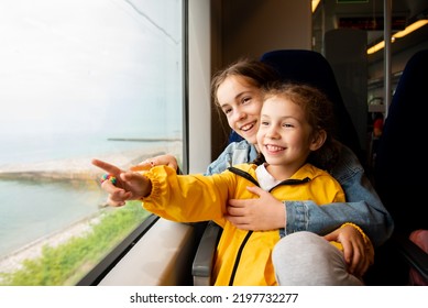 Dve sestry dievčatá sa pozerajú z okna vlaku na more. Dievčatá sa rozprávajú a bavia sa. Cesta. Reflexia. Dovolenka. leto. Rodinná dovolenka.