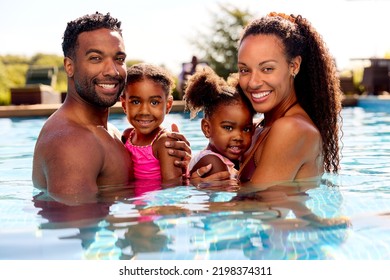Portraitfamill op Summervakanz mat zwee Meedercher, déi an der Schwämm vun den Elteren ofgehale ginn