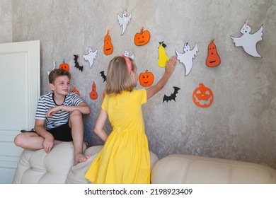 Children hang a garland for the Halloween party on the wall.